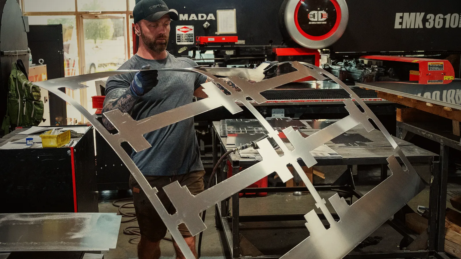 An operator lifting a punched aluminum skeleton off the turret punch
