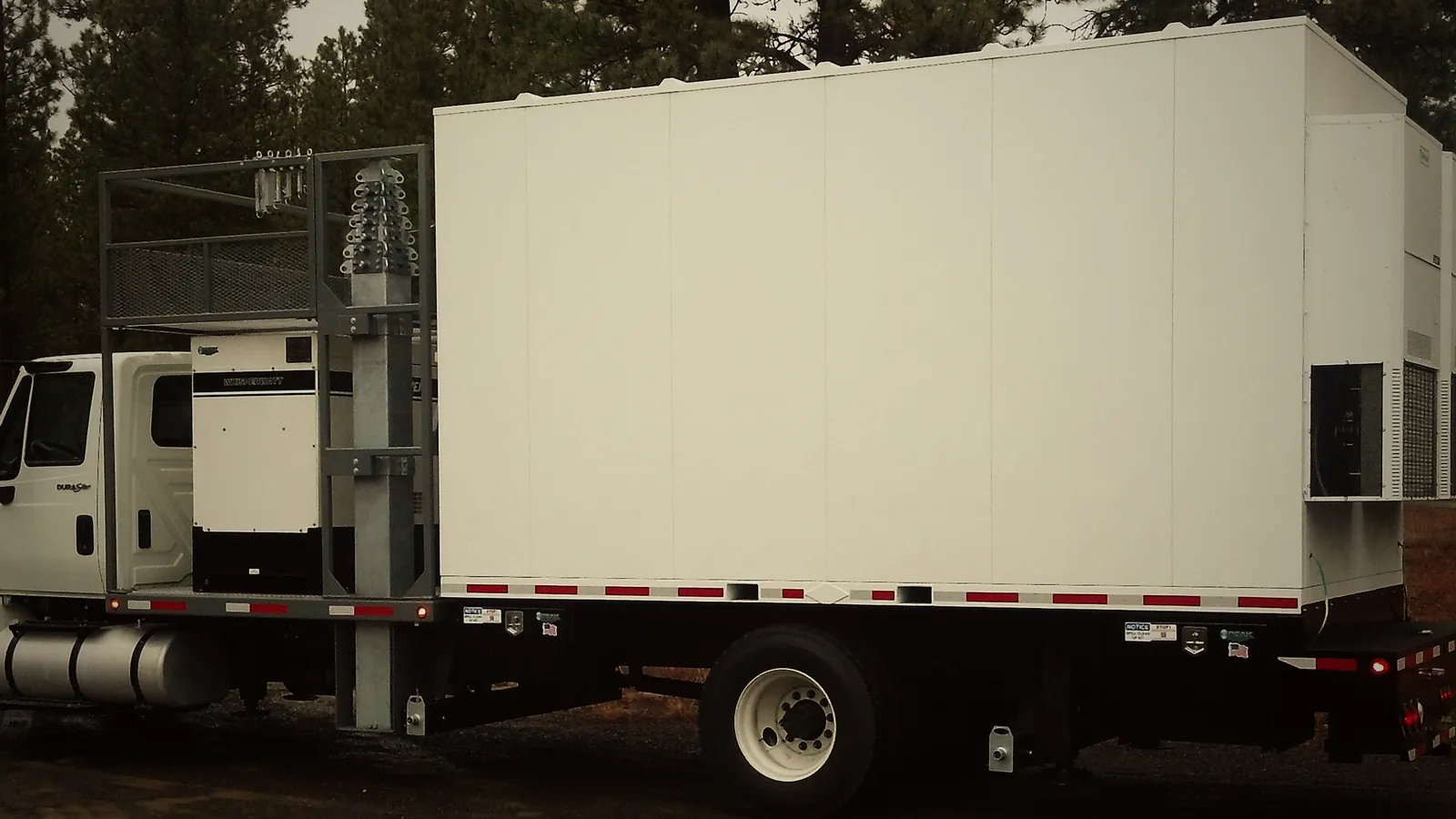 A Premier shelter mounted on a truck, parked among pine trees