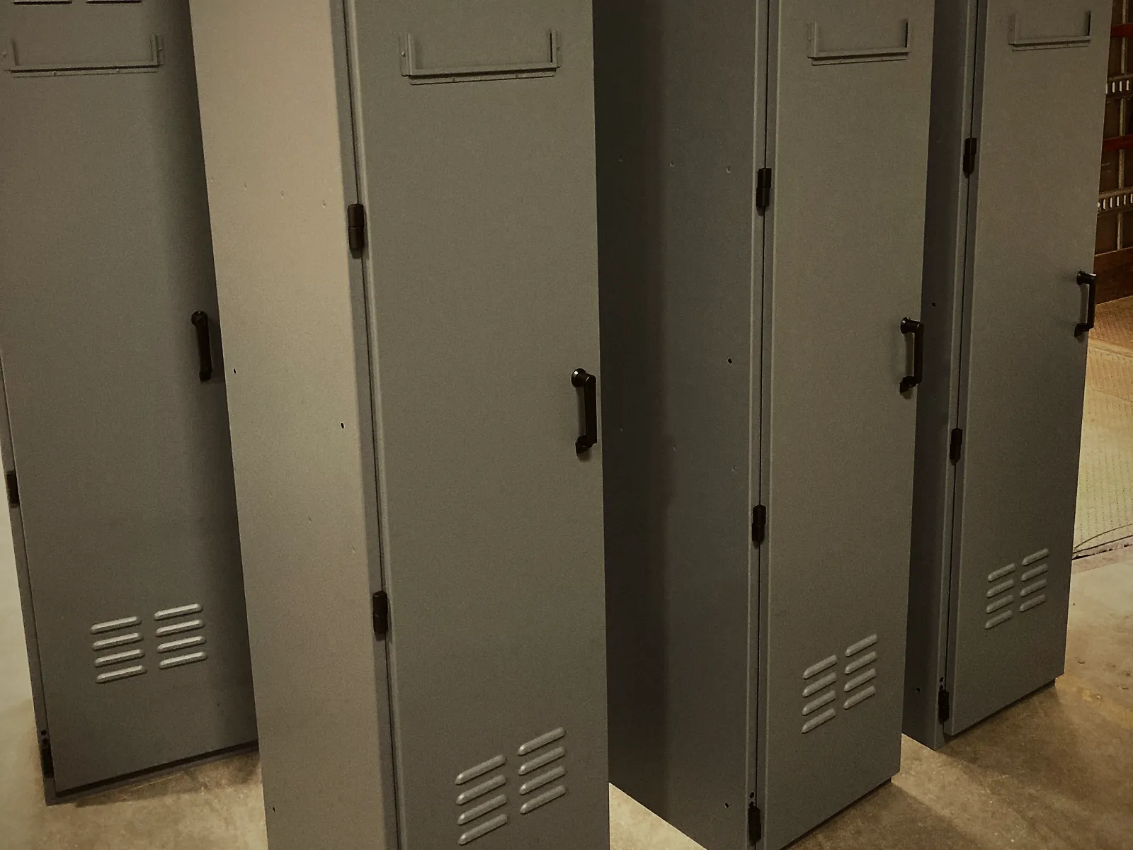 Tall louvered outdoor cabinets, powder coated grey, standing in the shop