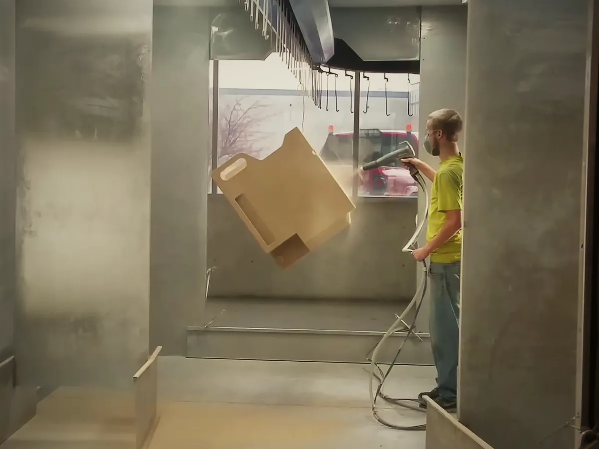 A coater spraying a part hanging on the powder line