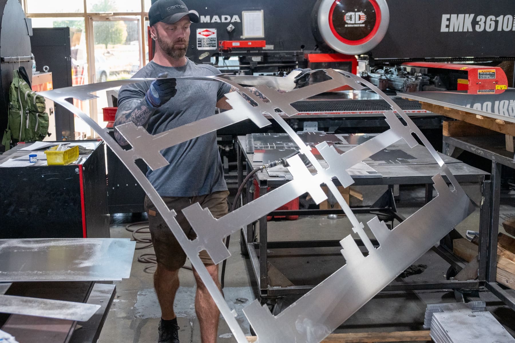 An operator holding up a large cut aluminum part