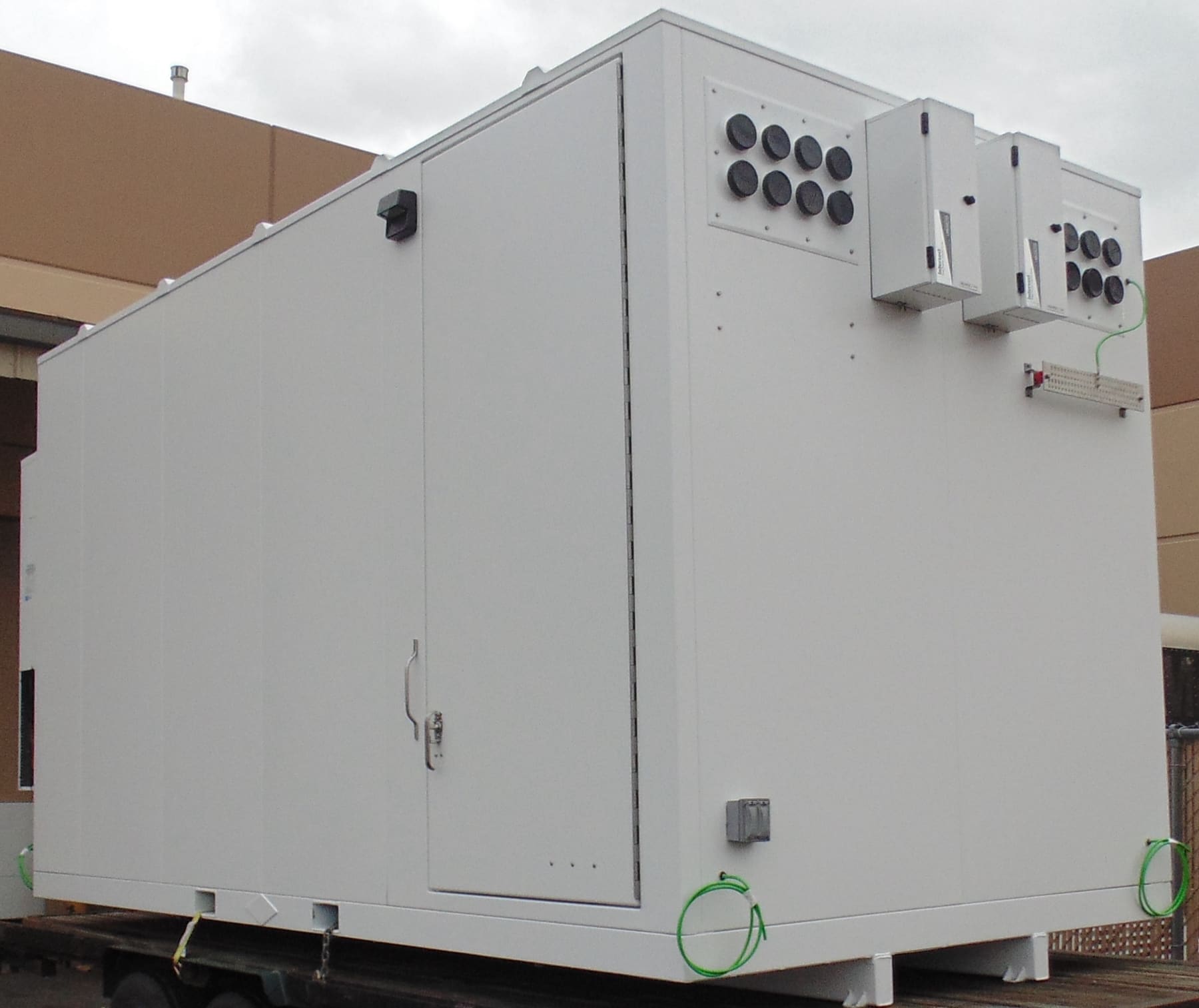 A white walk-in telecom equipment shelter